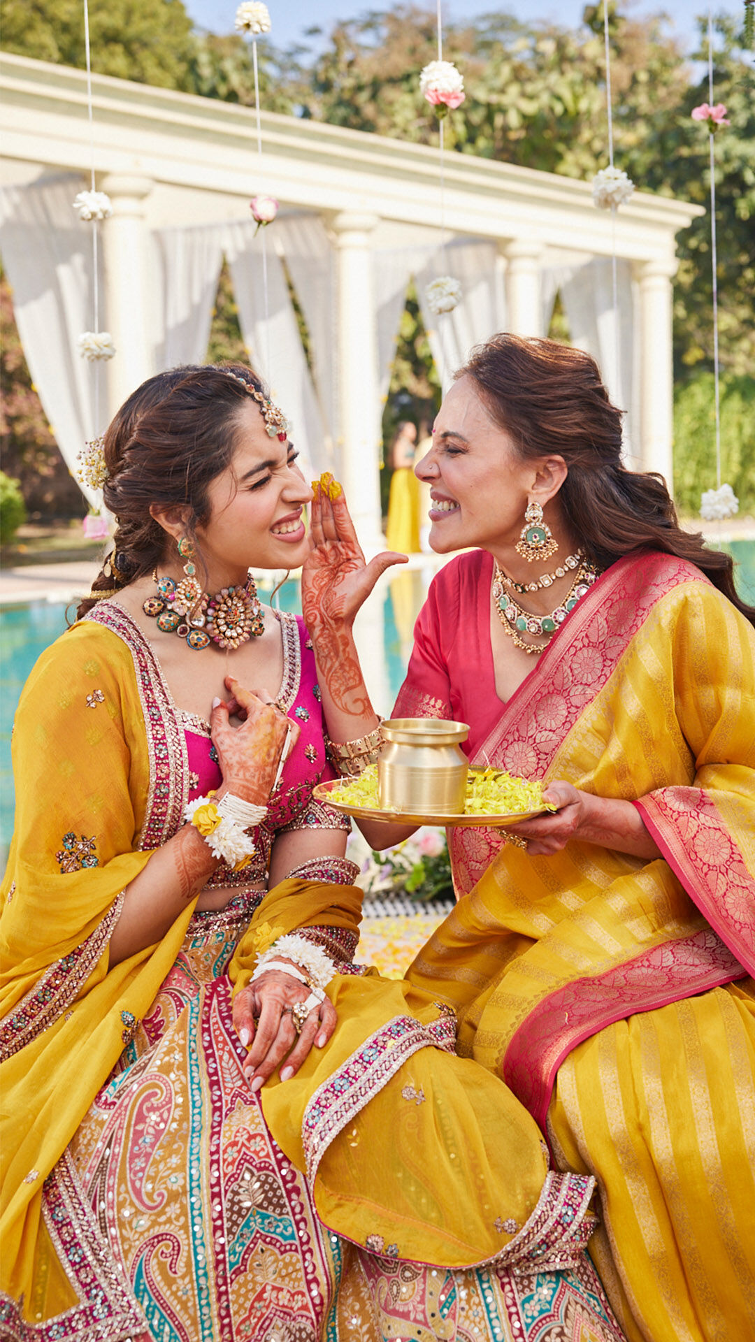 bride and her grandmother wearing yellow sarees and yellow lehenga with rhinestone work